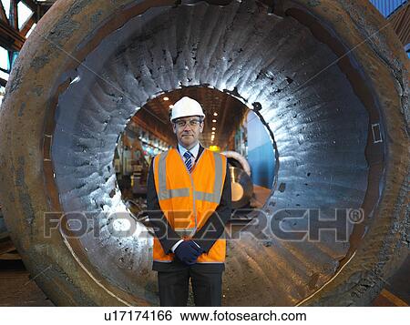 Stock Photograph - Engineer In Front Of Forged Steel. Fotosearch