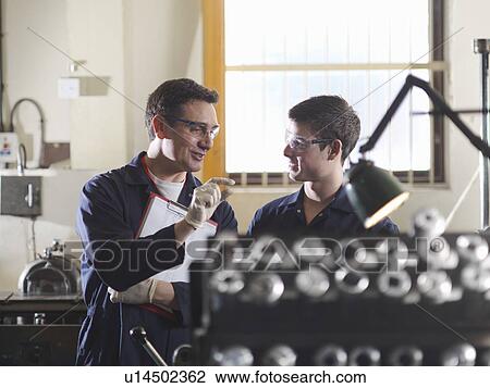 Stock Image - Experienced Engineer Teaching Apprentice. Fotosearch