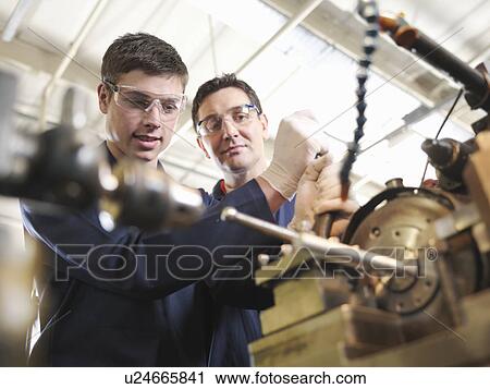 Stock Image - Experienced Engineer Teaching Apprentice. Fotosearch