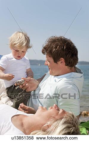 Family at the beach looking at shells View Large Photo Image Stock Photo - Family at the beach looking at shells. Fotosearch