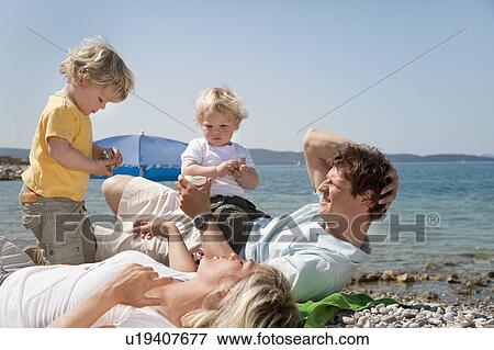 Family at the beach looking at shells View Large Photo Image Stock Photo - Family at the beach looking at shells. Fotosearch