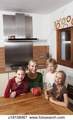 Family in kitchen with piggy bank View Large Photo Image Stock Photo - Family in kitchen with piggy bank. Fotosearch
