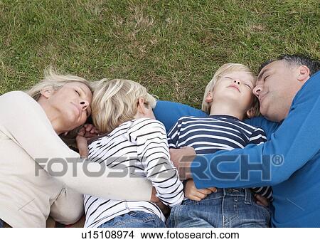 Picture - Family lying down together on grass. Fotosearch
