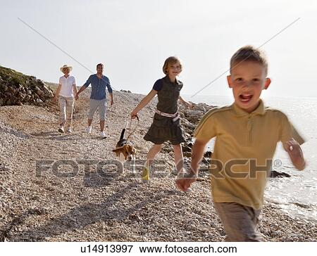 Stock Photo - Family with dog running at the beach. Fotosearch