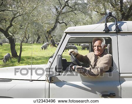 Stock Photograph - Farmer in 4x4 looking out of window. Fotosearch