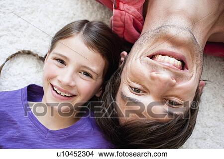 Picture - Father and girl lying on carpet. Fotosearch