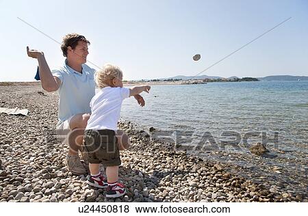 Father and son throw stones at beach View Large Photo Image Stock Photo - Father and son throw stones at beach. Fotosearch