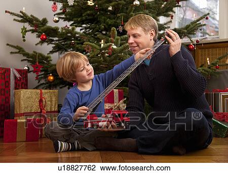 Stock Image - father, son play with christmas present. Fotosearch