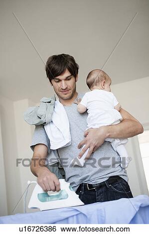 Stock Photograph - Father with baby in arm ironing. Fotosearch