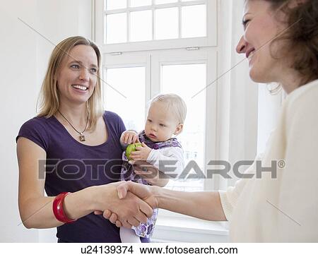 Picture - Female advisor shaking a mother's hand. Fotosearch
