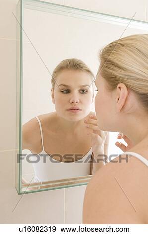 Stock Photo - Female beauty inspecting skin in mirror. Fotosearch