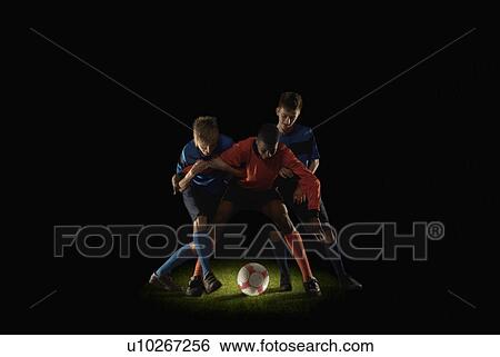 Stock Photograph - Footballers competing for ball. Fotosearch