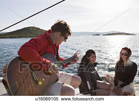 Stock Photography - Friends with guitar on yacht. Fotosearch