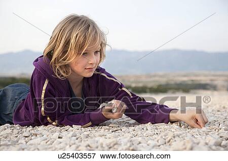 Stock Photo - Girl collecting stones at the beach. Fotosearch