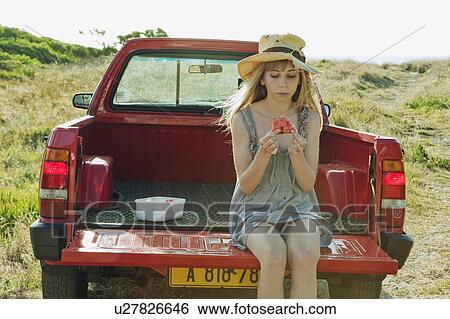 Stock Photograph - Girl eating watermelon on back of truck. Fotosearch