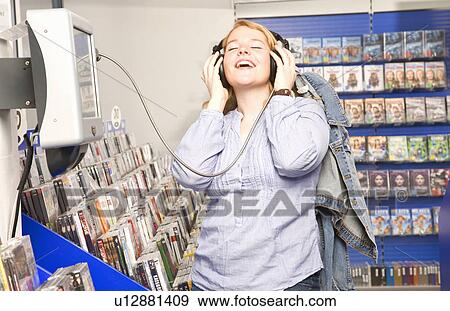 Girl enjoys listening some music in shop View Large Photo Image Stock Photo - Girl enjoys listening some music in shop. Fotosearch