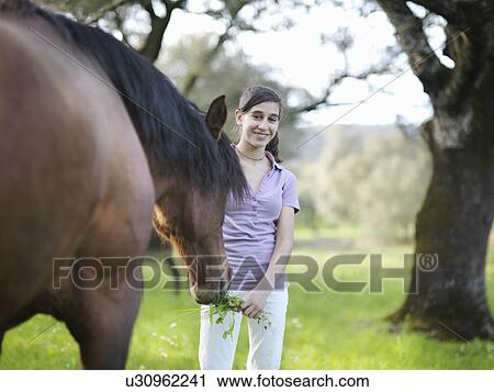 Girl giving grass to horse View Large Photo Image Stock Image - Girl giving grass to horse. Fotosearch
