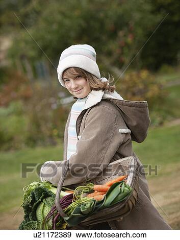 Stock Photo - Girl holding basket of vegetables. Fotosearch
