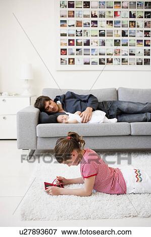 Stock Photo - Girl playing while father resting. Fotosearch