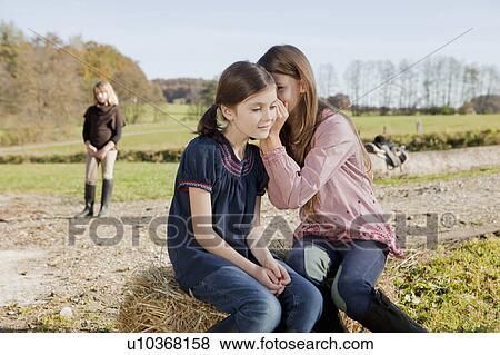 Girl speaking in her friends ear View Large Photo Image Stock Photo - Girl speaking in her friends ear. Fotosearch