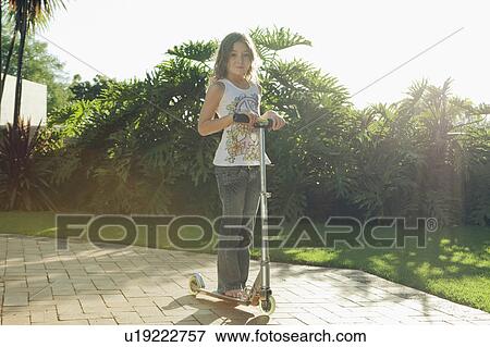 Girl standing on scooter View Large Photo Image Stock Photo - Girl standing on scooter. Fotosearch