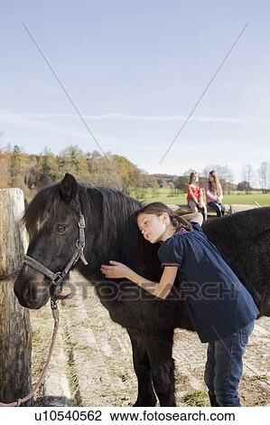 Stock Image - Girl stroking a pony. Fotosearch