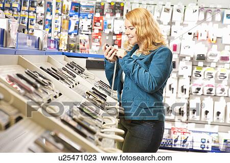 Stock Image - Girl testing mobile phones in the shop. Fotosearch