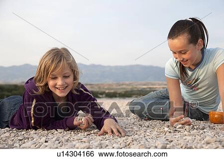 Girls collecting stones at the beach View Large Photo Image Stock Photograph - Girls collecting stones at the beach. Fotosearch