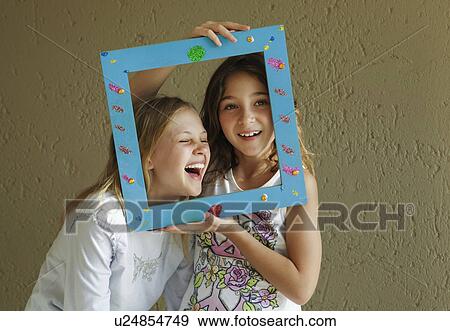 Stock Photo - Girls looking through picture frame. Fotosearch