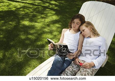 Girls reading book together View Large Photo Image Stock Photograph - Girls reading book together. Fotosearch