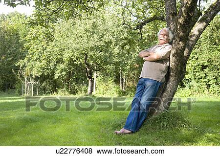Stock Photo - Grandfather is leaning against a tree. Fotosearch
