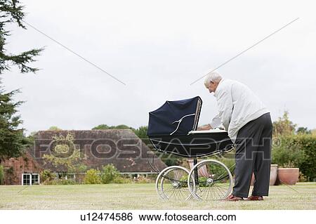 Stock Photograph - Grandfather looking at baby in pram. Fotosearch