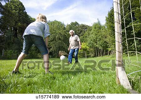 Stock Photo - Grandfather tries to score a goal. Fotosearch