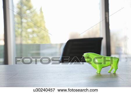 Stock Photo - Green bull standing on conference table. Fotosearch