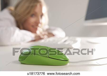 Stock Photograph - Green mouse on office desktop with woman. Fotosearch