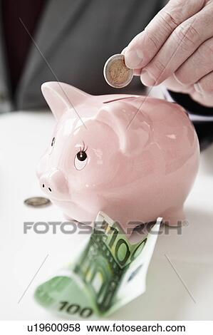 Hand putting coin into piggy bank View Large Photo Image Stock Photo - Hand putting coin into piggy bank. Fotosearch