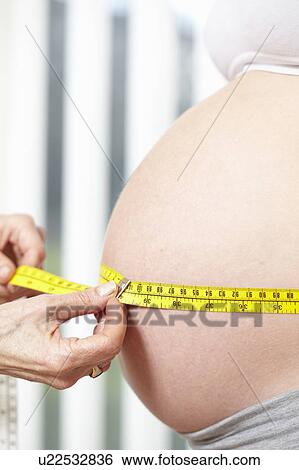 Stock Photograph - Hands measuring pregnant belly. Fotosearch