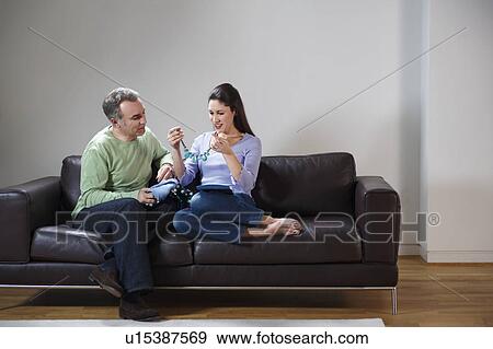 Stock Photo - Happy couple opening presents on couch. Fotosearch