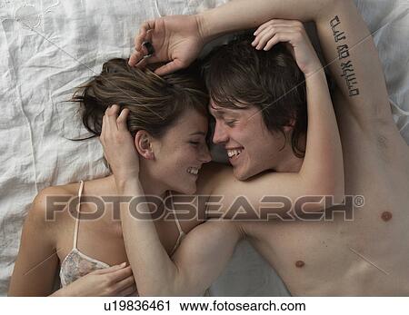 Happy young couple lying on bed View Large Photo Image Stock Image - Happy young couple lying on bed. Fotosearch