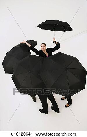 Stock Image - Jubilant women with umbrella checks rain. Fotosearch