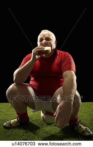 Large footballer, sitting on ball eating View Large Photo Image Stock Image - Large footballer, sitting on ball eating. Fotosearch