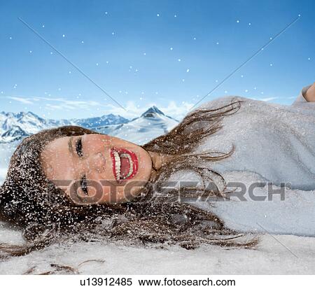 Stock Photography - Laughing woman lays in fallen snow. Fotosearch