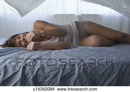 Picture - Laughing young woman lying on bed. Fotosearch