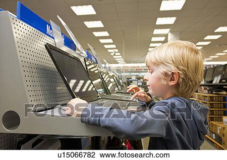 Stock Image - Little boy is testing a laptop computer. Fotosearch