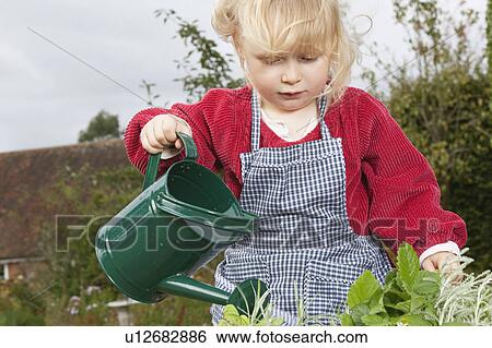 Stock Photograph - Little girl watering plants in garden. Fotosearch