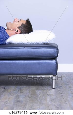 Stock Photography - lying man singing with music in ears. Fotosearch