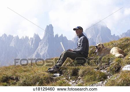 Man and dog in mountains with laptop View Large Photo Image Stock Image - Man and dog in mountains with laptop. Fotosearch
