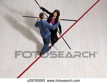 Stock Image - Man and woman balancing on thin red line. Fotosearch