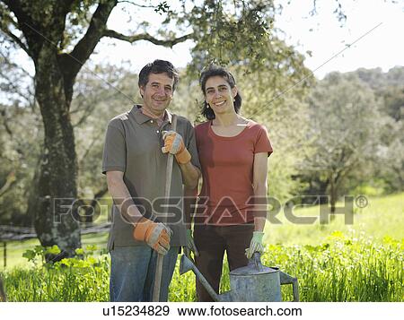 Stock Photo - Man and woman posing with watering can. Fotosearch