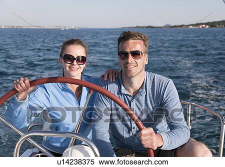 Stock Photography - Man and woman steering yacht. Fotosearch